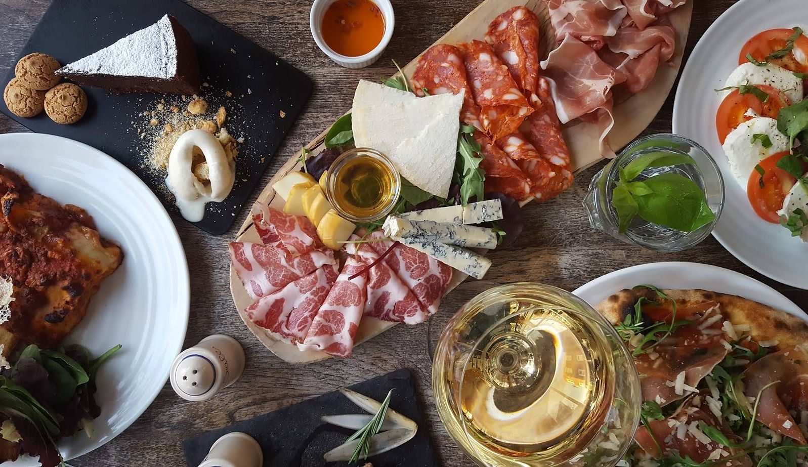 A sharing board of cured meats and cheese, with wine